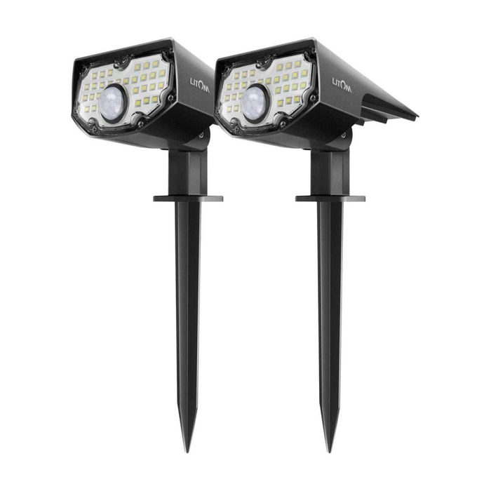Two black LED outdoor lights are mounted on stakes, designed to illuminate areas with motion detection, suitable for garden or pathway lighting.