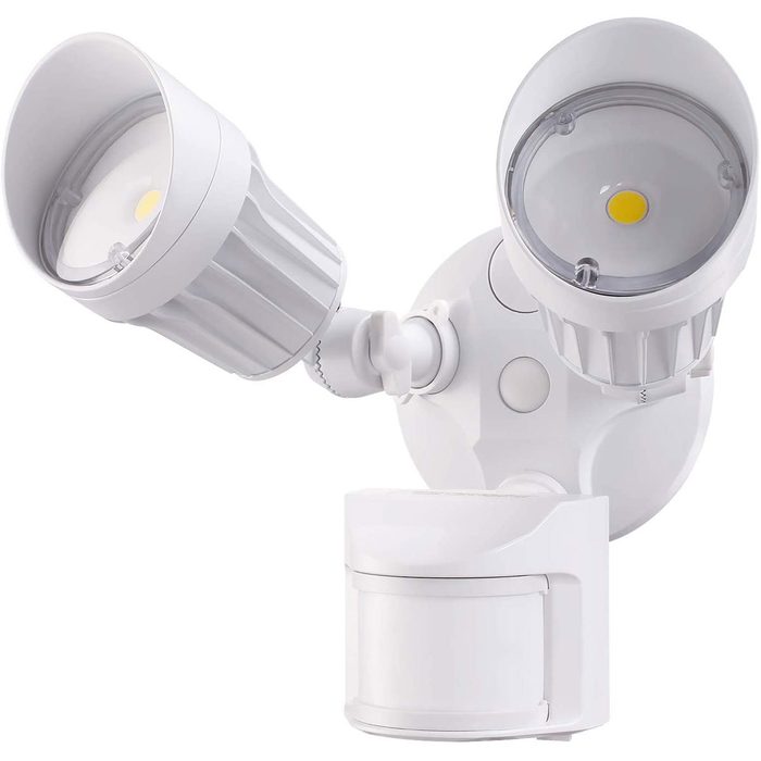 A dual-headed outdoor motion sensor light is mounted on a white base, illuminating an area while detecting nearby movement in its environment.