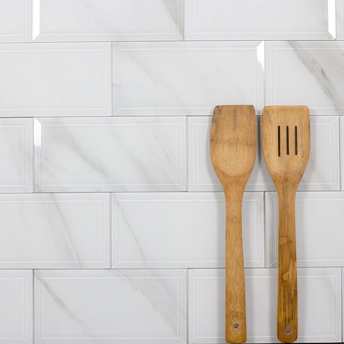 Two wooden spatulas rest on a smooth, light-colored tiled surface that resembles marble, creating a clean and modern kitchen ambiance.