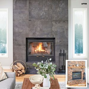 A modern fireplace with a lit fire sits against a dark stone wall, surrounded by a cozy living room featuring plants and natural light from large windows.