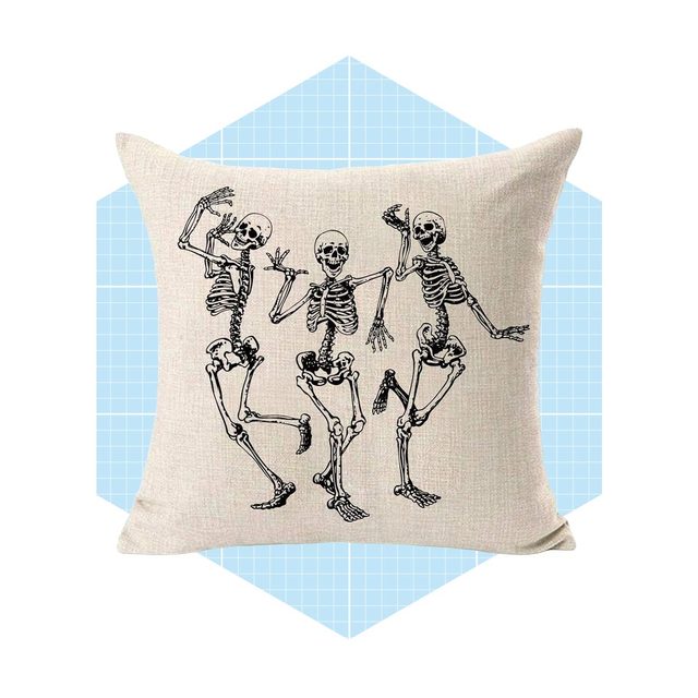 A decorative pillow features three dancing skeletons, each with a different pose, set against a light blue geometric background.