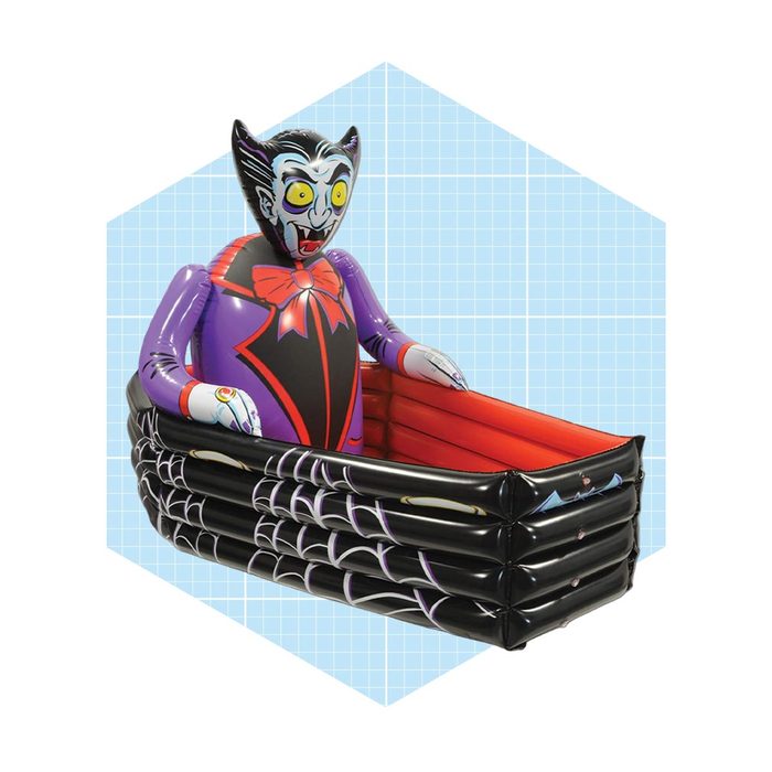 An inflatable vampire figure is sitting in a black coffin-shaped boat, surrounded by a grid-patterned light blue background.
