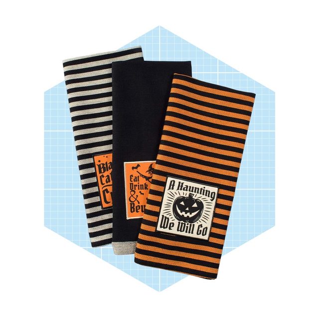 Three decorative towels featuring Halloween-themed designs and colors rest against a light blue grid background, featuring stripes and seasonal phrases.