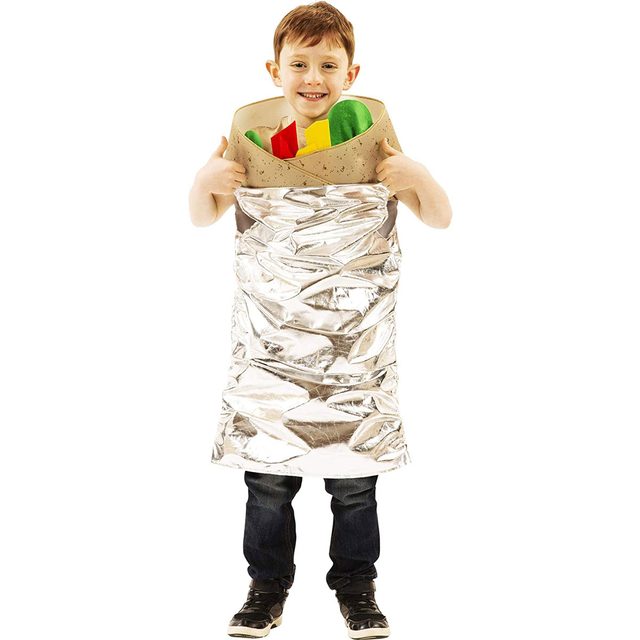 A child wearing a shiny foil burrito costume smiles while standing, holding it up with a colorful filling of felt vegetables visible inside.