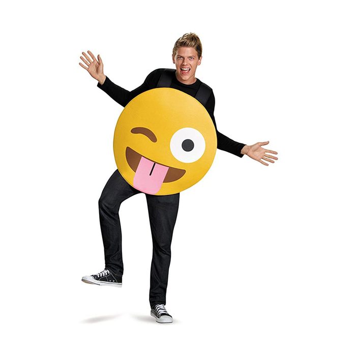 A person wears a large, smiling emoji costume, playfully posing with arms raised in a bright space, exuding a cheerful, fun atmosphere.