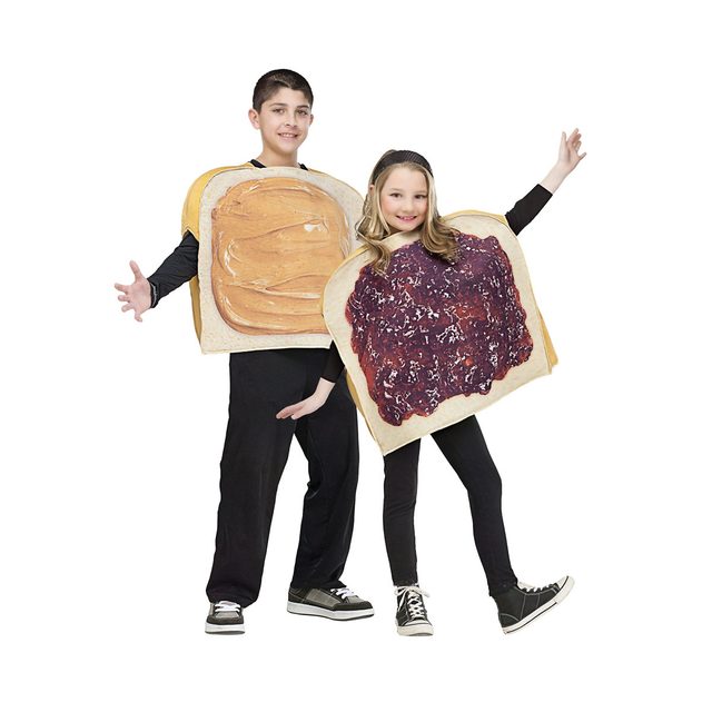 Two children dressed in sandwich-themed costumes pose playfully, one resembling peanut butter and the other jelly, against a plain white background.