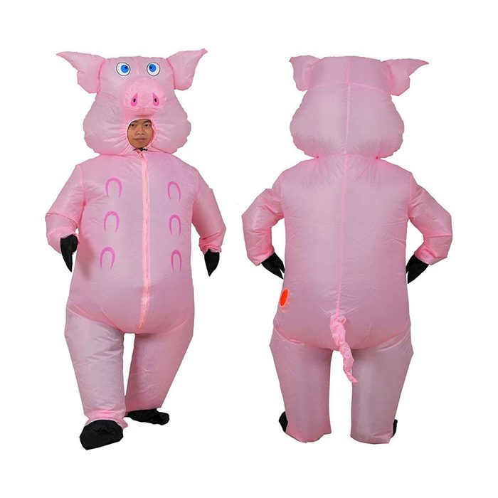 An inflatable pig costume stands upright, arms at sides; a person inside wears a mask mimicking a pig's face, with black gloves and a tail.