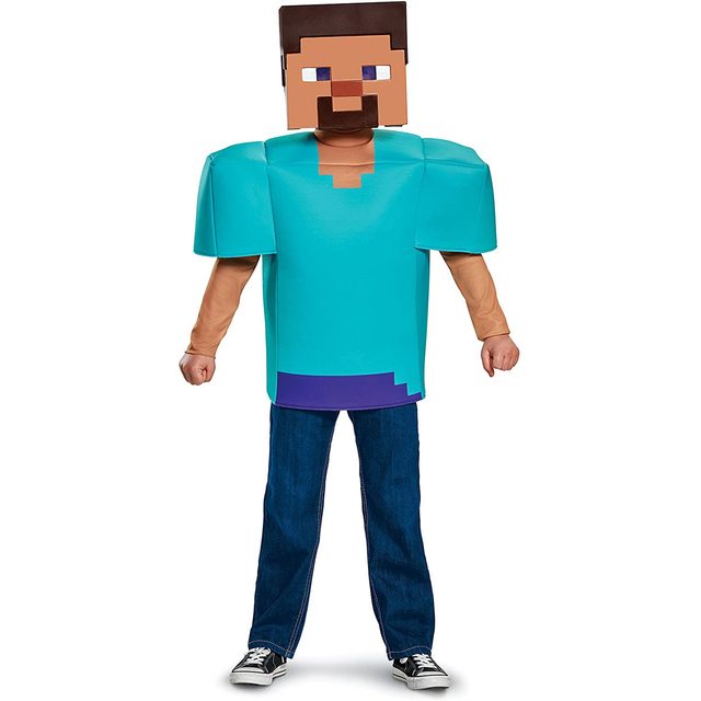 A child wears a large, cube-shaped head costume and oversized shirt resembling a video game character, standing confidently in casual pants and shoes.