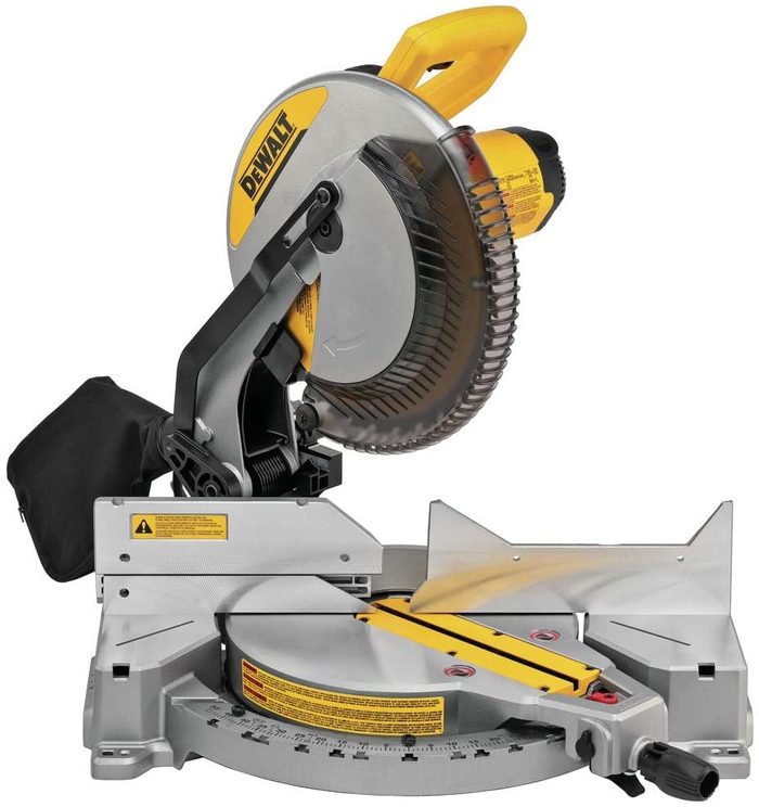 A miter saw rests on a stable base, ready for use, featuring a circular blade aimed downward, intended for precise wood cutting in a workshop setting.