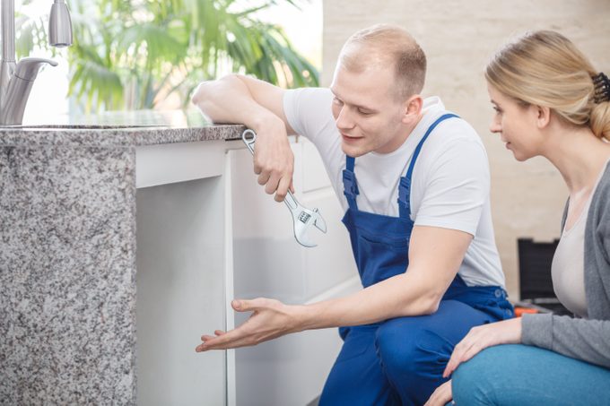 Plumber holding a wrench talking with a housewife about faucet damage