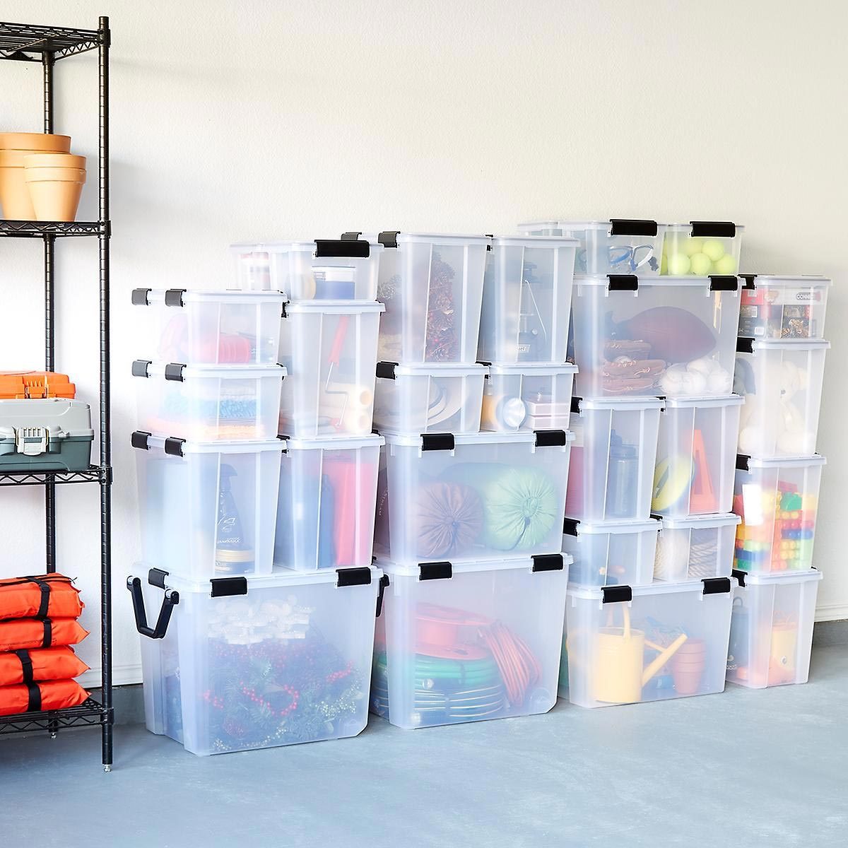 Clear storage containers are stacked neatly in a corner, holding various supplies. A metal shelf with pots is nearby, in a well-lit indoor space.