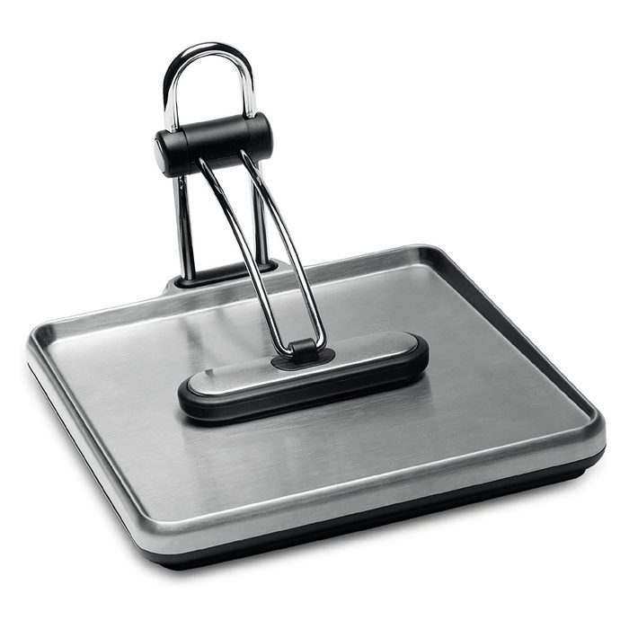 A stainless steel panini press rests on a flat surface, featuring a black handle for pressing, designed to heat and flatten sandwiches efficiently.