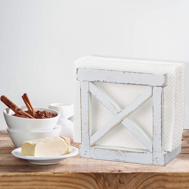 A paper towel holder displays stacked towels beside bowls of cocoa powder and cinnamon sticks, with a plate of butter on a wooden surface.