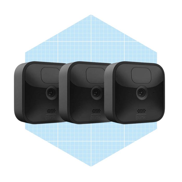 Three identical black security cameras are arranged in a row, positioned against a light blue geometric background that features a grid pattern.