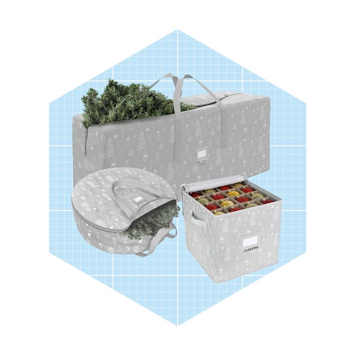Three storage containers, holding greenery and ornaments, are arranged against a light blue grid background, showcasing their festive designs and practical handles.