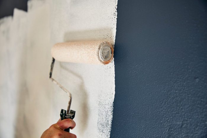 Close Up On A Pain Roller Spreading Paint On A Wall.