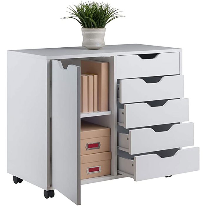 A white storage cabinet features multiple drawers and a section with boxes, topped with a potted plant, set against a neutral background.