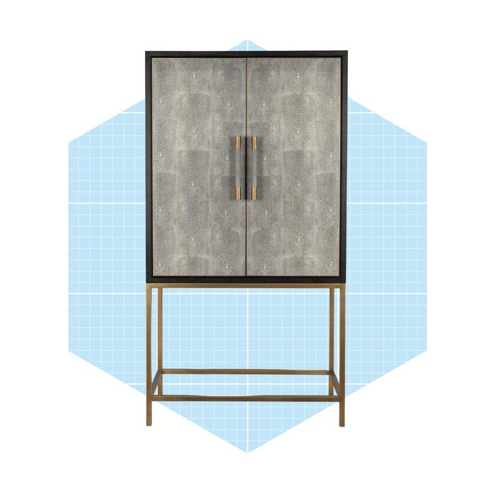 A decorative cabinet stands upright, featuring dual gray doors with bronze handles, set against a light blue, grid-patterned background.
