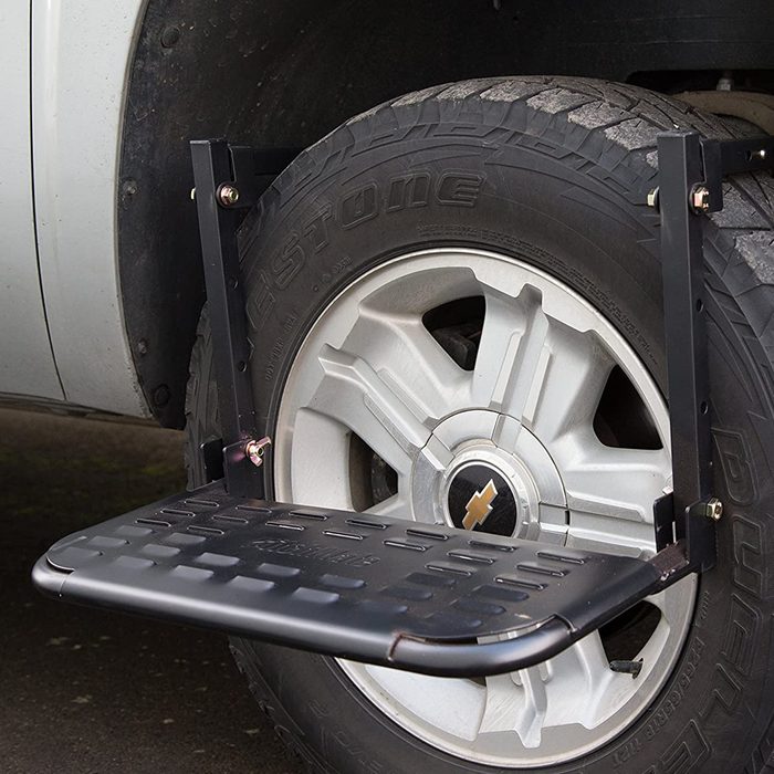 A sturdy step is attached to a vehicle's tire, providing a platform for easy access. The setting is outdoor, near a vehicle with a Chevrolet logo.