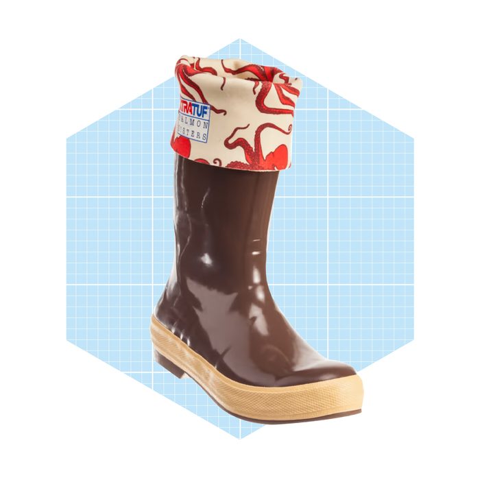 A brown rubber boot stands upright, featuring a patterned red and white cuff. It is displayed against a light blue grid background.
