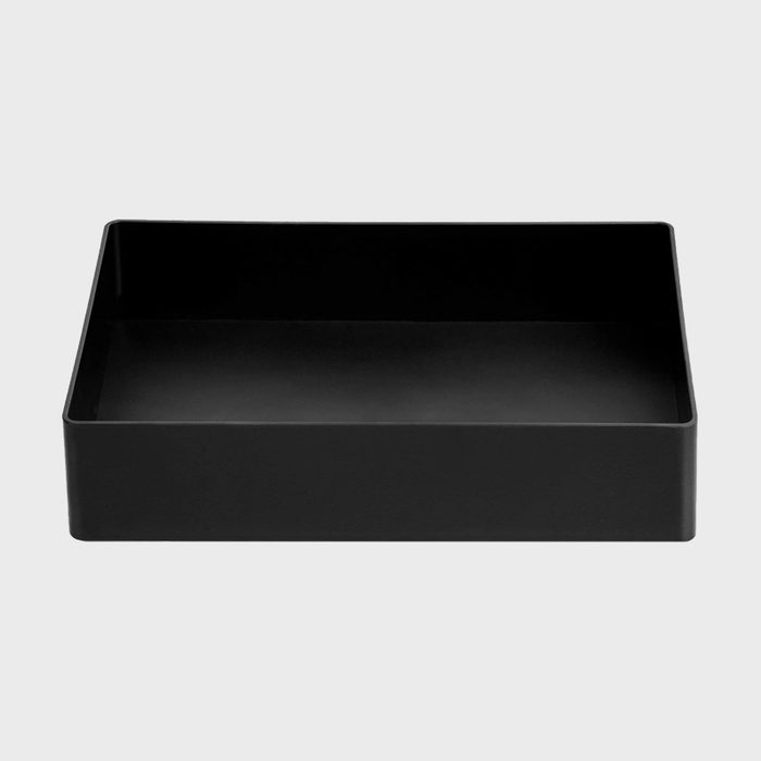 A rectangular black tray sits on a light gray surface, designed for organizing or holding items within its open space.