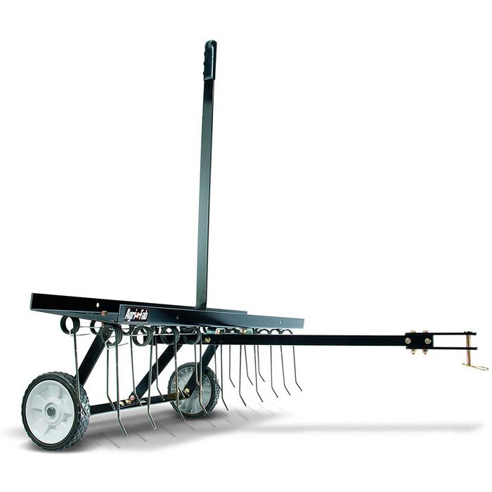 A lawn dethatcher, featuring a long handle and multiple metal tines, is designed to remove thatch while being pushed across grassy terrain on two wheels.