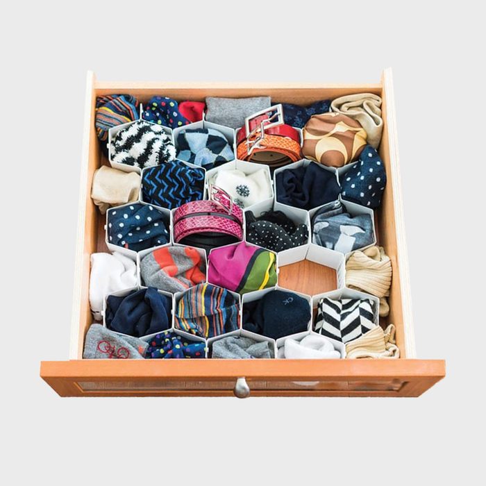 A wooden drawer organizes rolled socks and accessories in hexagonal compartments, showcasing a variety of colors and patterns in a neat arrangement.