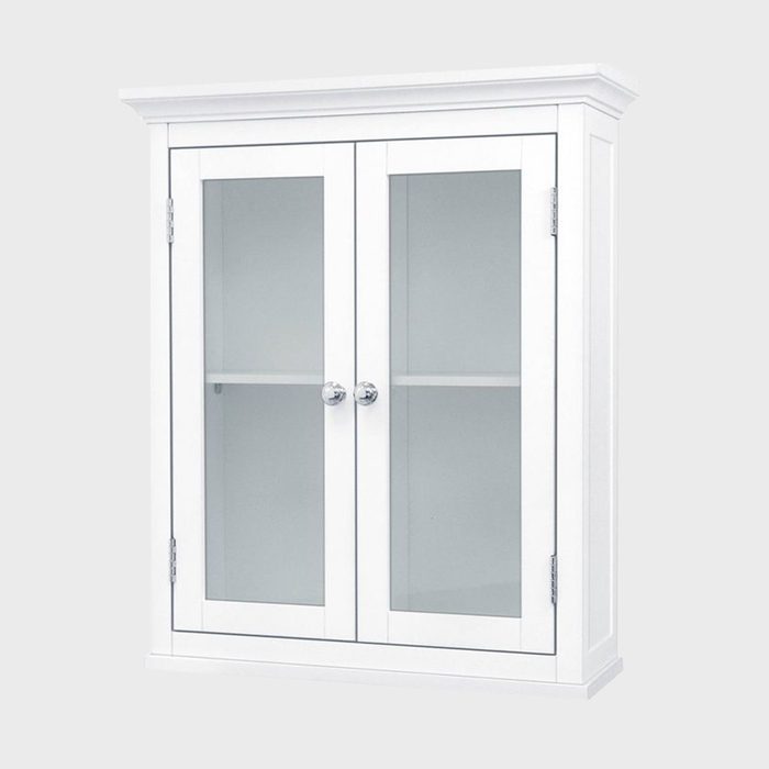 A white display cabinet stands upright, featuring glass doors and shelves, designed to showcase items within a neutral, minimalistic space.