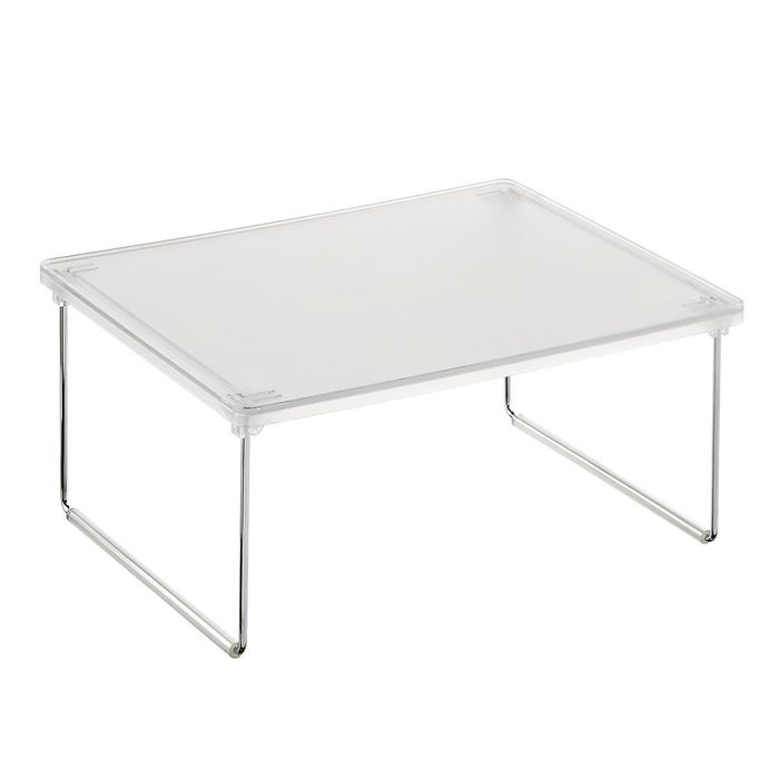 A clear acrylic coffee table rests on metal legs, providing a minimalist surface for displaying items or serving drinks in a modern interior setting.