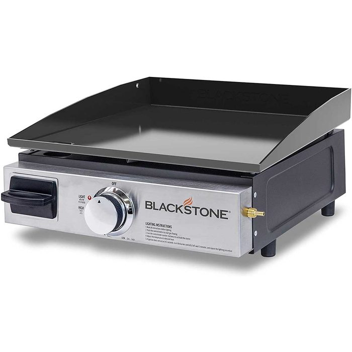 A stainless steel griddle with a flat cooking surface heats food, featuring a control knob and a gas connection, ideal for outdoor cooking.