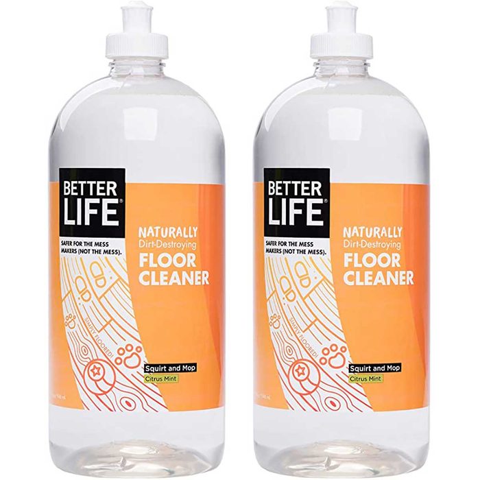 Two transparent bottles of floor cleaner stand side by side, featuring an orange label that promotes a naturally dirt-destroying formula in a citrus mint scent.