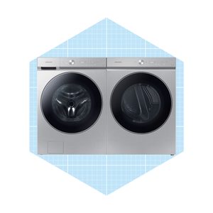 A silver washing machine and dryer sit side by side, featuring circular viewing windows, on a light blue grid-patterned background.
