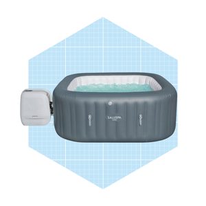 An inflatable hot tub, filled with water, is positioned against a light blue grid background, showing what appears to be bubbling water.