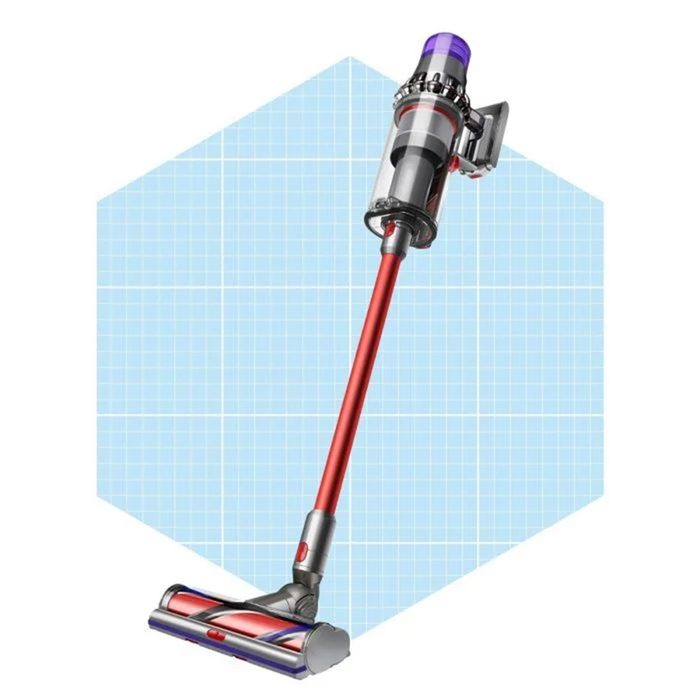 A cordless vacuum cleaner stands upright, with a long red handle and a specialized head, set against a light blue grid-patterned background.