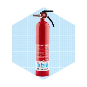 A red fire extinguisher stands upright, labeled with instructions. It is set against a light blue grid background, indicating safety and readiness for use.