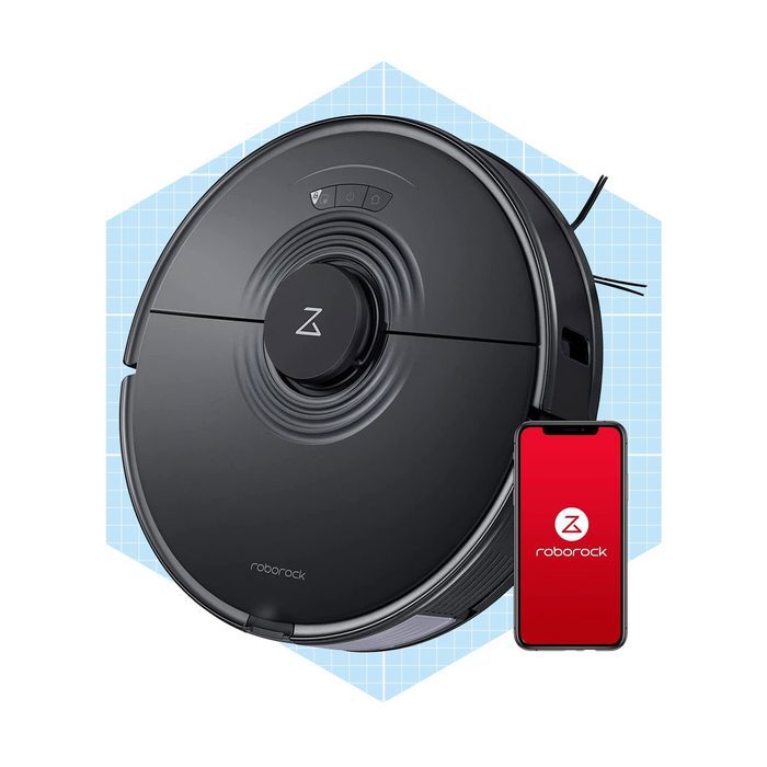 A round black robotic vacuum sits beside a smartphone, indicating it's operational within a simple geometric background, likely illustrating a modern cleaning solution.