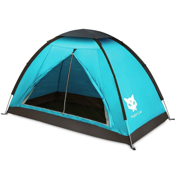 A vibrant blue tent stands upright, featuring an open entrance, designed for camping outdoors, suggesting a recreational setting in nature.