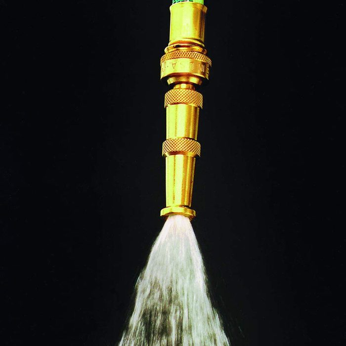 A gold-colored hose nozzle emits a spray of water against a dark background, creating a misty effect.