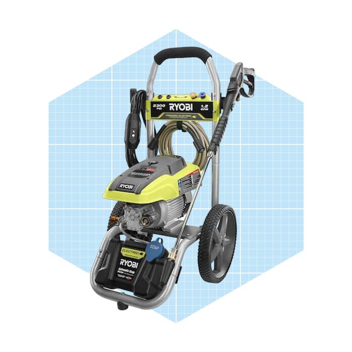 A Ryobi pressure washer stands upright, equipped with hoses and wheels, ready to clean surfaces effectively in residential settings.
