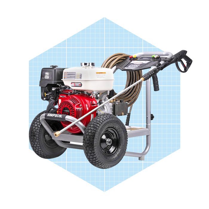 A red and black pressure washer with wheels is parked, ready for use, featuring a spray gun, hoses, and a protective frame against a blue grid background.