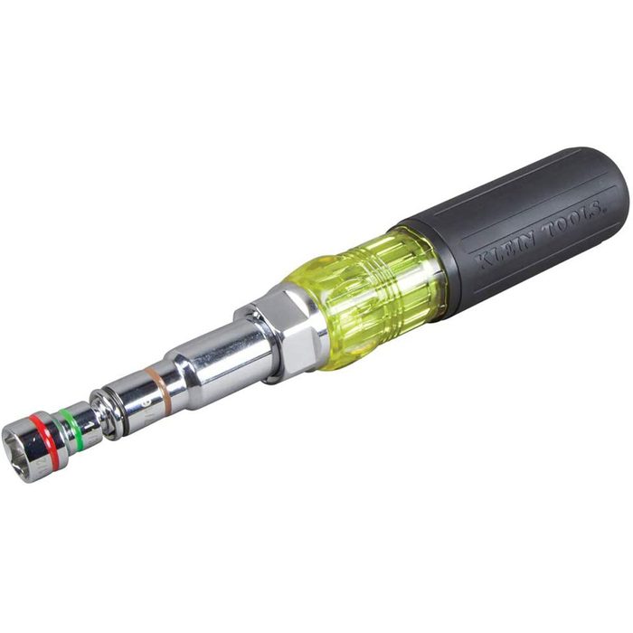 A screwdriver with a chrome shaft and a bright yellow handle is positioned horizontally, showcasing its interchangeable socket at one end in a neutral background.