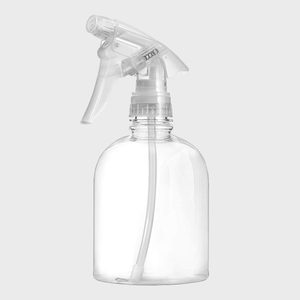 A clear spray bottle stands upright, with a nozzle positioned at the top. It is set against a plain gray background, appearing empty.