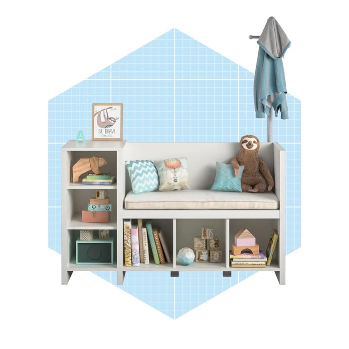 A cozy bench adorned with colorful pillows holds a plush toy, surrounded by a shelf of books and decorative items, against a light blue grid background.