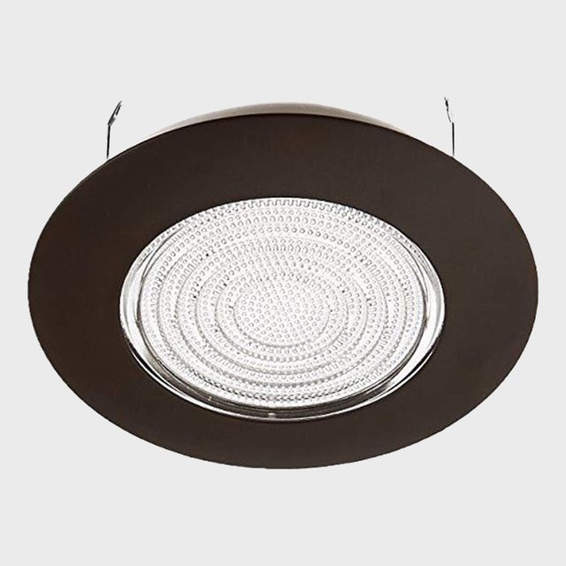 A round ceiling light fixture illuminates a space, featuring a patterned diffuser surrounded by a dark, circular frame, mounted from the ceiling.