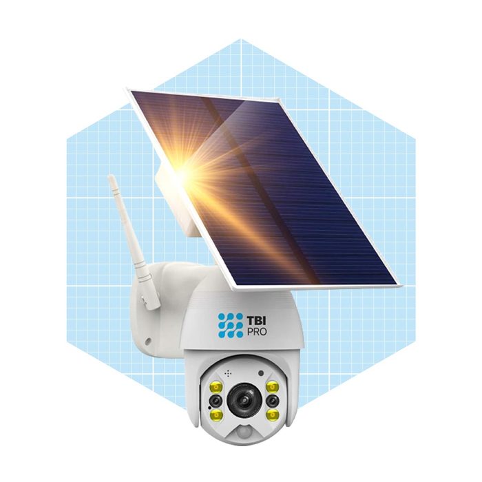 A surveillance camera with a solar panel is mounted on a wall, capturing energy from sunlight while detecting movement in its surroundings.