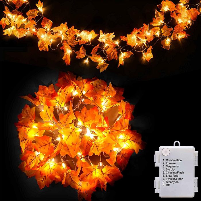 String lights with orange leaves illuminate a dark background, creating a warm, cozy ambiance; a control box lists various lighting modes.