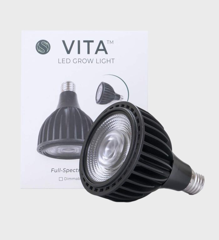 A black LED grow light is positioned in front of its packaging, featuring details about its full-spectrum capabilities and dimmable function.