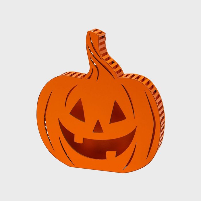 An orange pumpkin-shaped decoration smiles, featuring cut-out eyes and a mouth, set against a plain light background, embodying a Halloween theme.