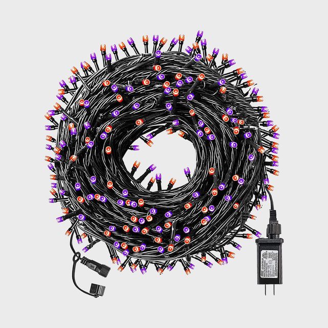 A coiled string of colorful holiday lights displays purple and orange bulbs, connected to a power adapter in a neutral background.