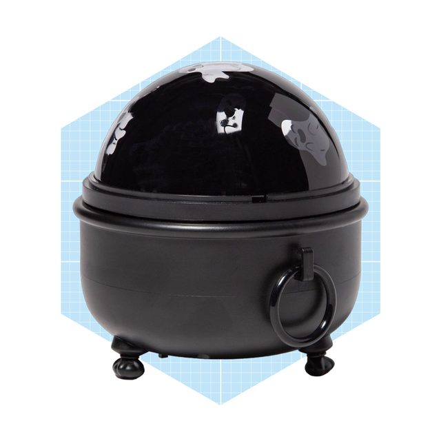 A black cauldron-like container with a shiny dome lid rests on three feet, set against a blue geometric background.